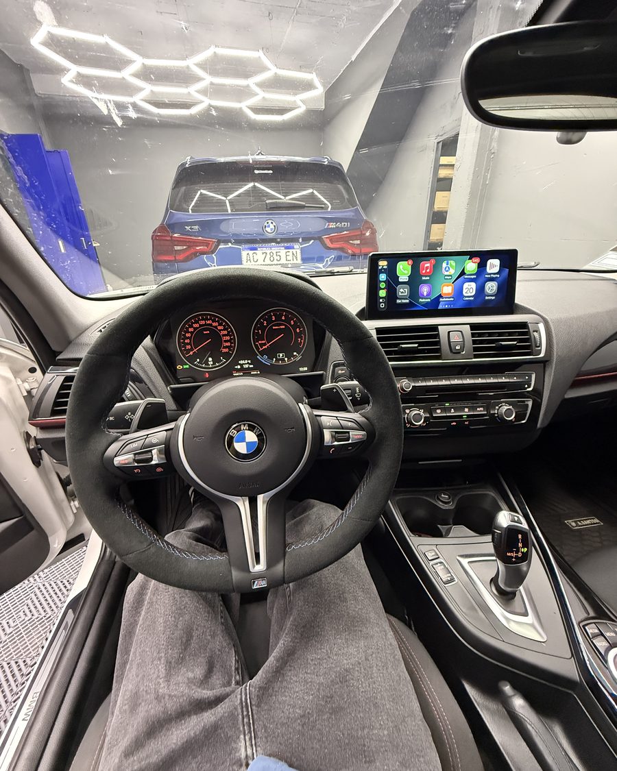 Volante M de alcántara instalado por BlumTech en un BMW Serie 1, con CarPlay en la pantalla